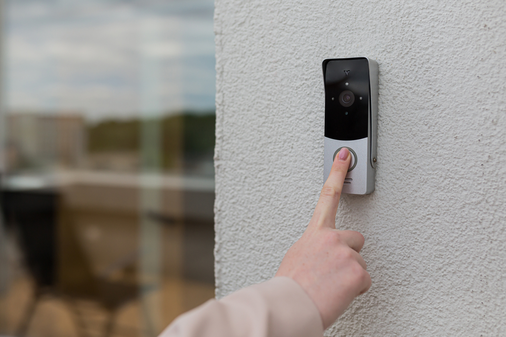 Woman's,Hand,Uses,A,Doorbell,On,The,Wall,Of,The